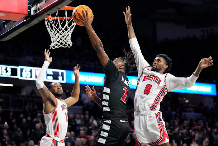 Cincinnati Bearcats guard Jizzle James (2) rises to the basket as Houston Cougars guard Mylik Wilson (8) defends in the second half of an NCAA college basketball game between the Houston Cougars and the Cincinnati Bearcats, Saturday, Feb. 10, 2024, at Fifth Third Arena in Cincinnati.